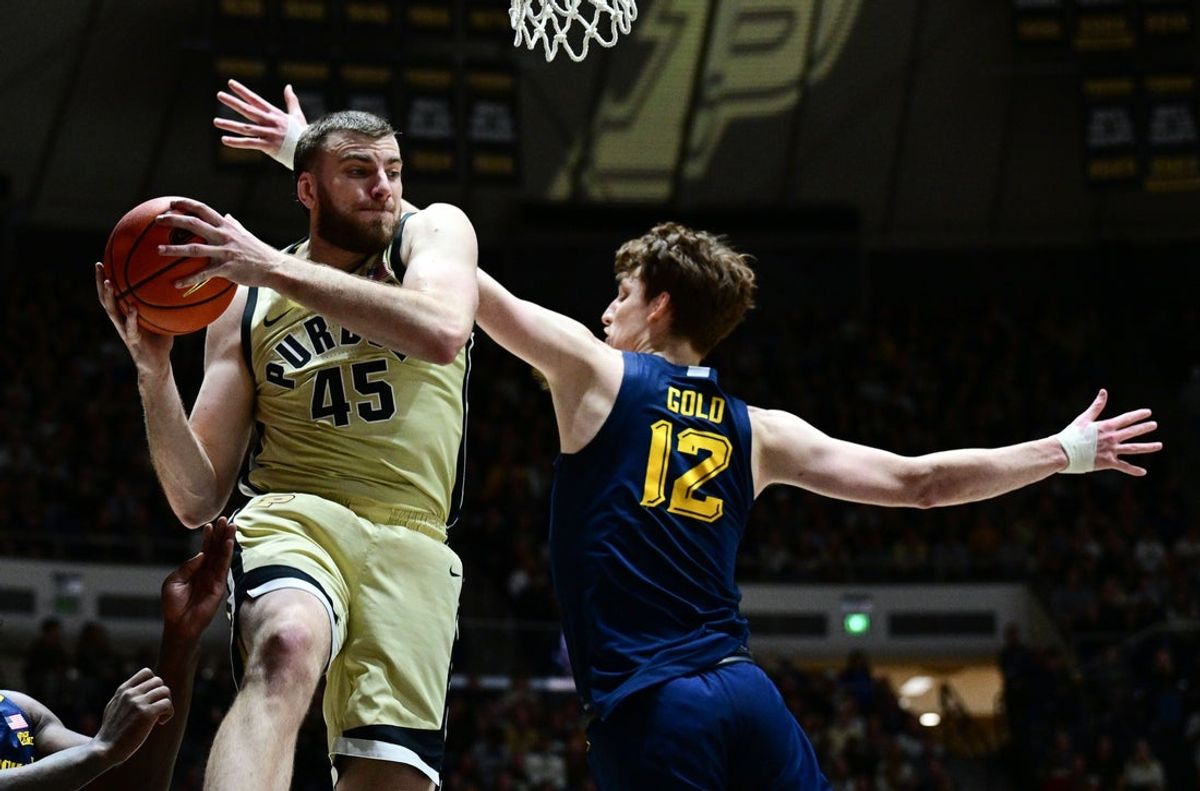 Dec 13, 2025; West Lafayette, Indiana, USA; Purdue Boilermakers center Oscar Cluff (45) grabs a rebound in front of Marquette Golden Eagles forward Ben Gold (12) during the first half at Mackey Arena. Mandatory Credit: Marc Lebryk-Imagn Images