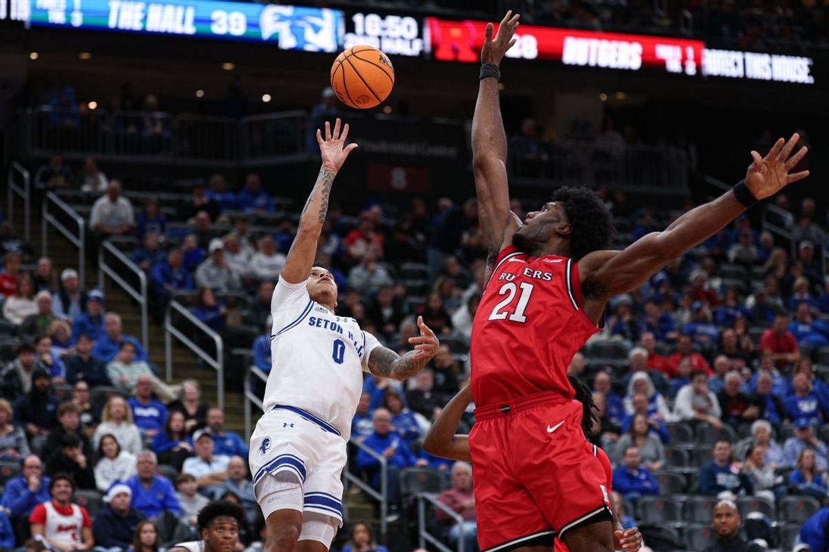 Dec 13, 2025; Newark, New Jersey, USA; Seton Hall Pirates guard Adam Clark (0) shoots the ball during the second half as Rutgers Scarlet Knights center Emmanuel Ogbole (21) defends at Prudential Center. Mandatory Credit: Vincent Carchietta-Imagn Images