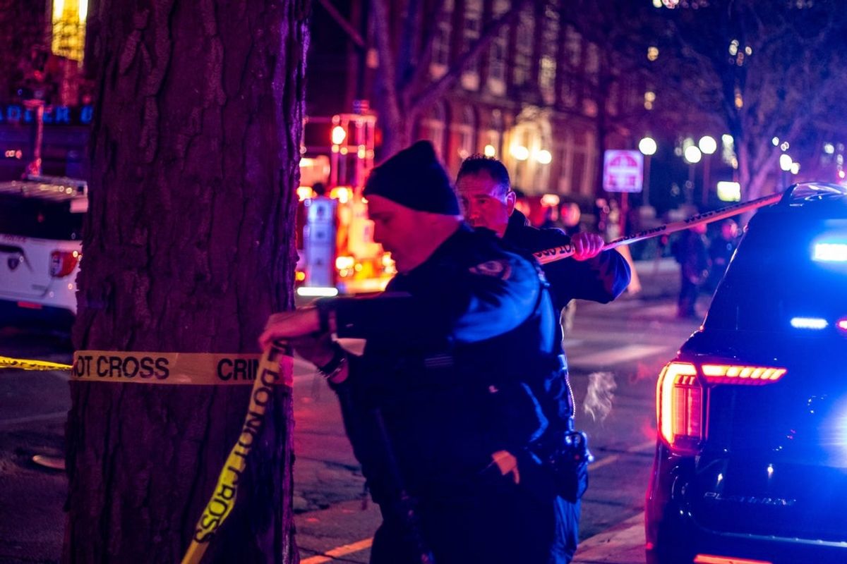 A police officer ties crime scene tape to a tree after expanding the crime scene following a mass shooting on Dec. 14, 2025.