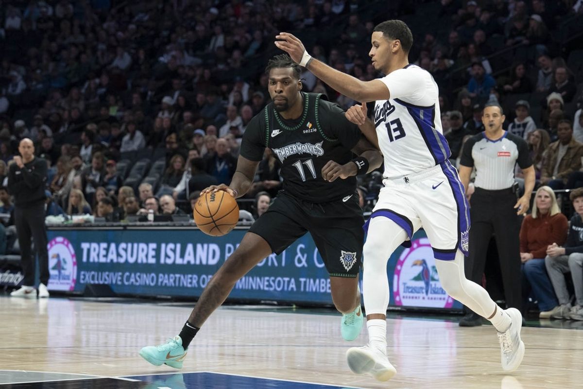 Dec 14, 2025; Minneapolis, Minnesota, USA; Minnesota Timberwolves center Naz Reid (11) dribbles the ball past Sacramento Kings forward Keegan Murray (13) in the first half at Target Center. Mandatory Credit: Jesse Johnson-Imagn Images
