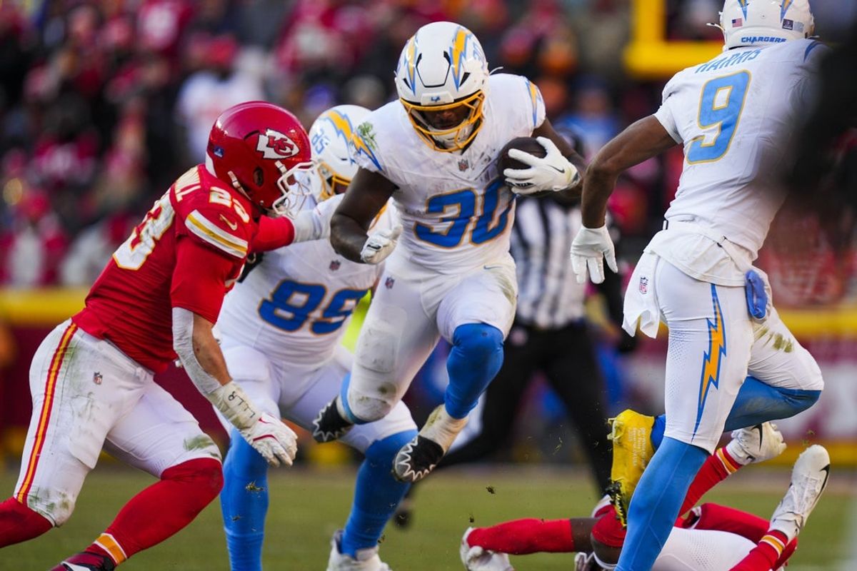 Dec 14, 2025; Kansas City, Missouri, USA; Los Angeles Chargers running back Kimani Vidal (30) rushes against Kansas City Chiefs linebacker Drue Tranquill (23) during the second quarter at GEHA Field at Arrowhead Stadium. Mandatory Credit: Jay Biggerstaff-Imagn Images
