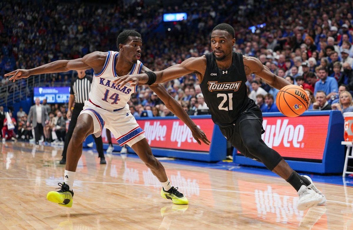 Dec 16, 2025; Lawrence, Kansas, USA; Towson Tigers guard Jack Doumbia Jr. (21) drives against Kansas Jayhawks guard Melvin Council Jr. (14) during the first half at Allen Fieldhouse. Mandatory Credit: Jay Biggerstaff-Imagn Images