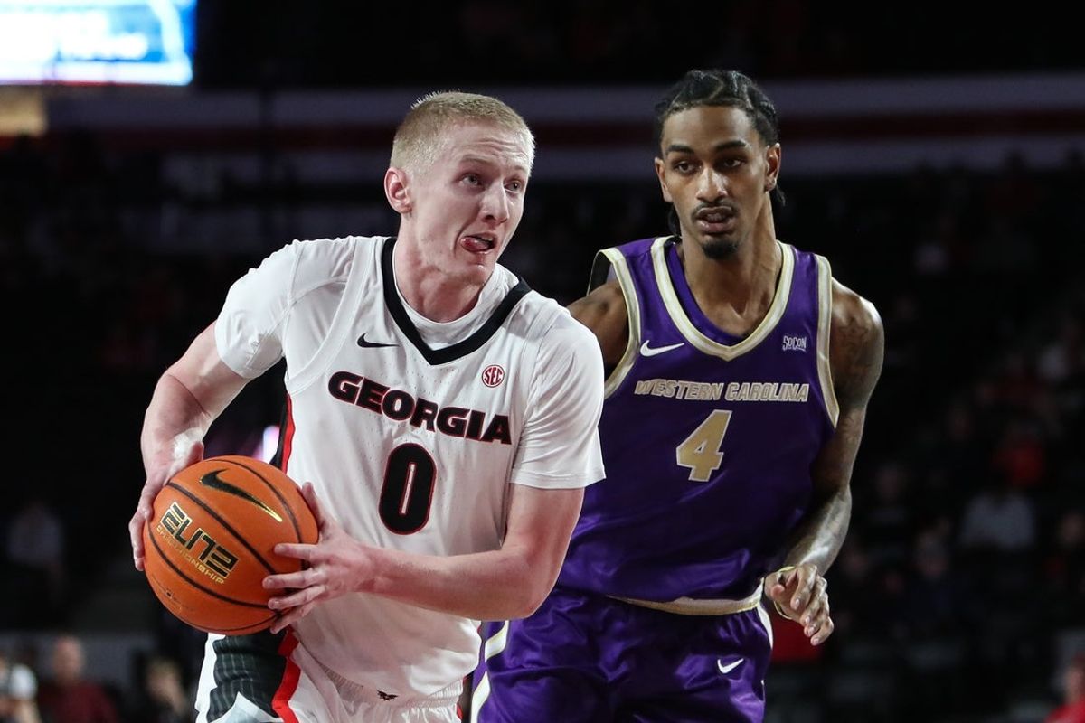 Dec 18, 2025; Athens, Georgia, USA; Georgia Bulldogs guard Blue Cain (0) drives past Western Carolina Catamounts guard Justin Johnson (4) in the first half at Stegeman Coliseum. Mandatory Credit: Mady Mertens-Imagn Images