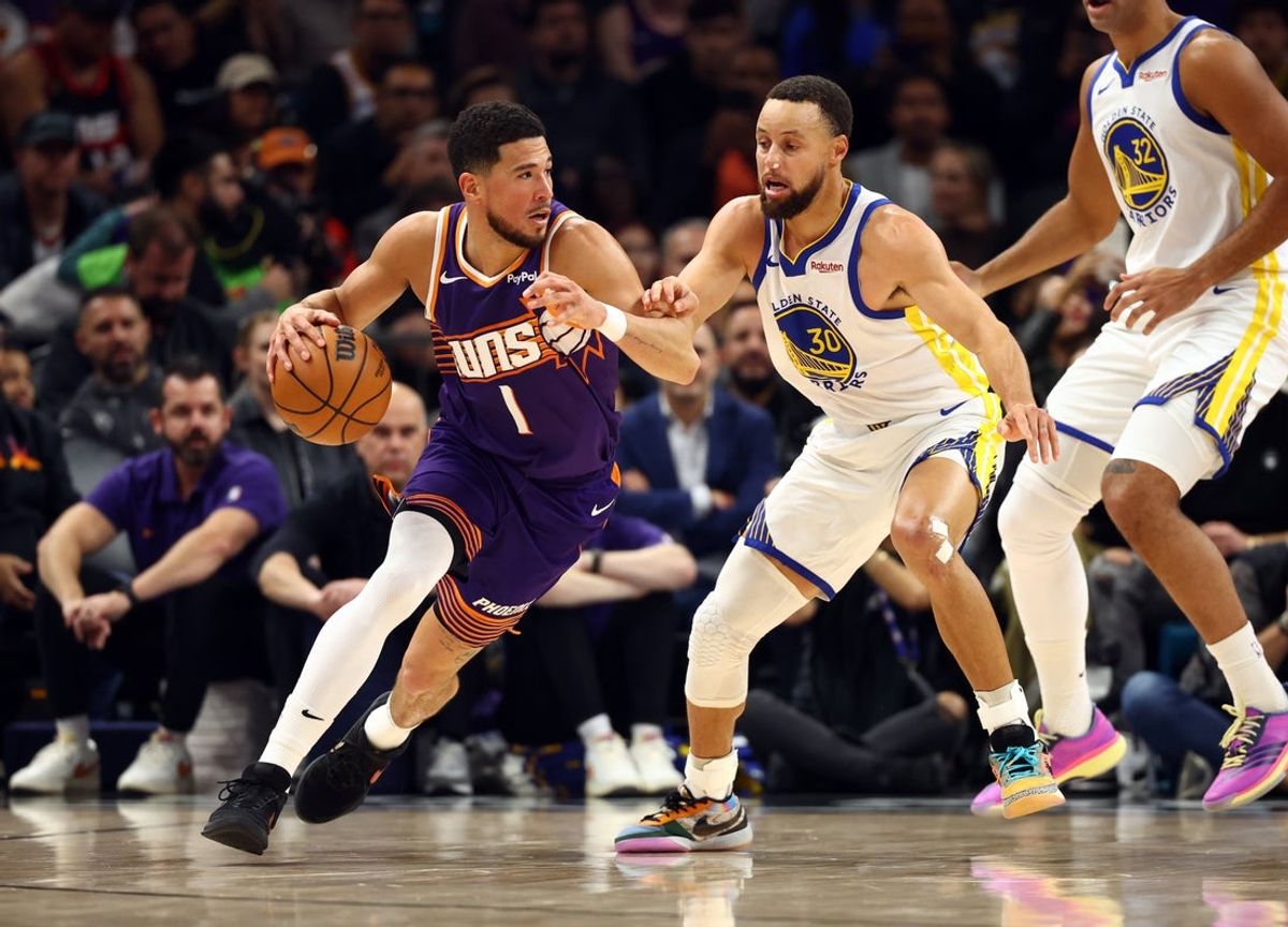 Dec 18, 2025; Phoenix, Arizona, USA; Phoenix Suns guard Devin Booker (1) against Golden State Warriors guard Stephen Curry (30) in the first half at Mortgage Matchup Center. Mandatory Credit: Mark J. Rebilas-Imagn Images