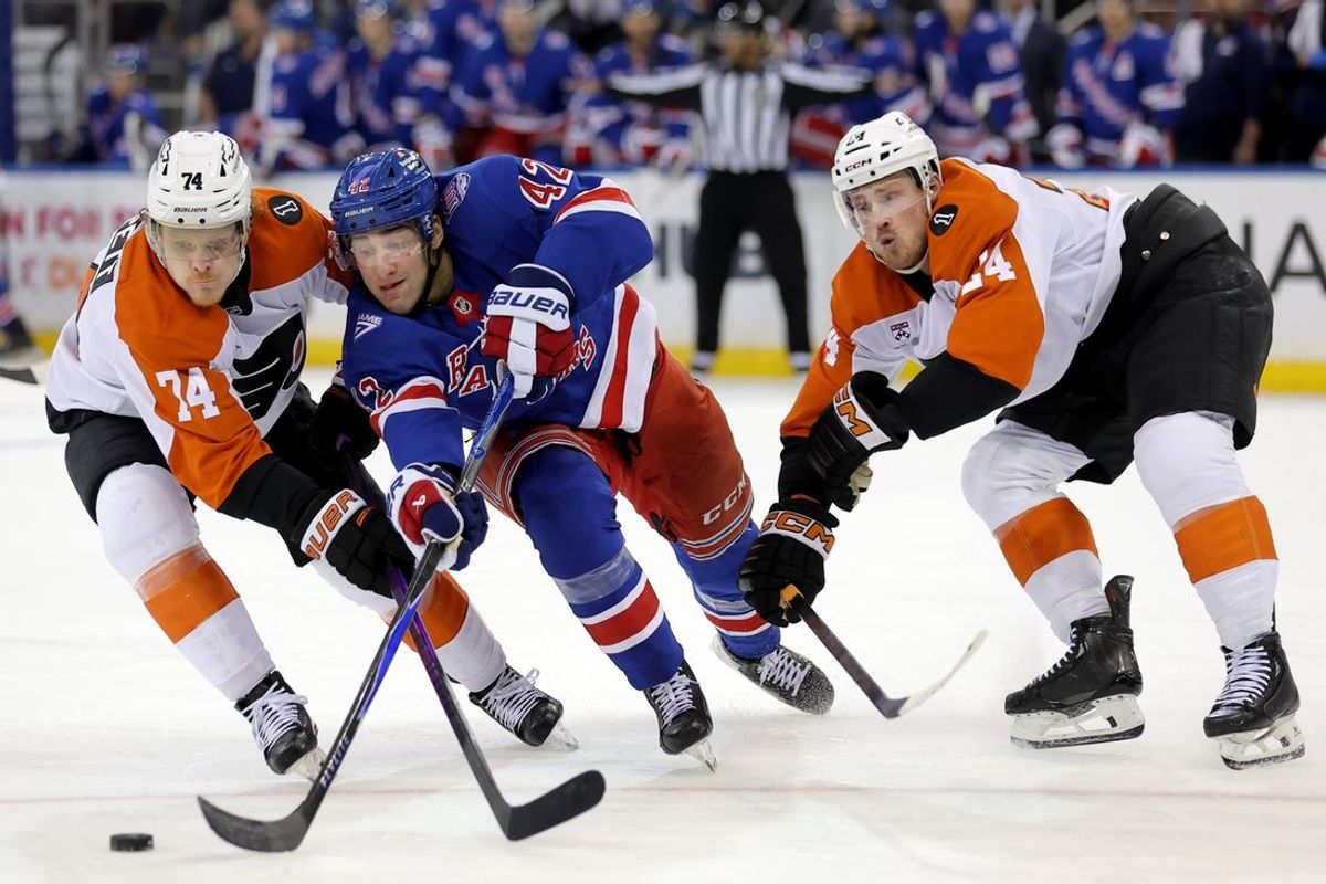 Dec 20, 2025; New York, New York, USA; New York Rangers center Noah Laba (42) fights for the puck against Philadelphia Flyers right wing Owen Tippett (74) and defenseman Nick Seeler (24) during the second period at Madison Square Garden. Mandatory Credit: Brad Penner-Imagn Images