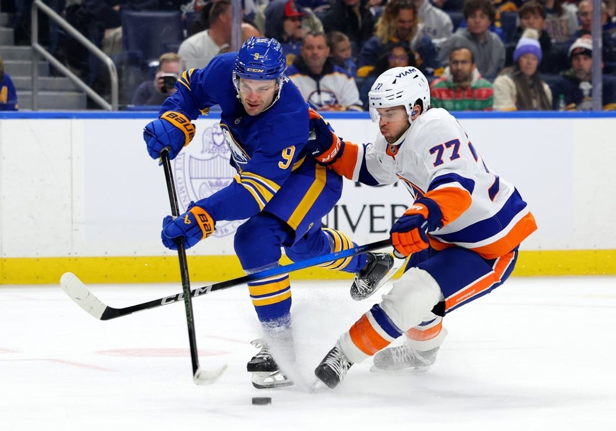 Dec 20, 2025; Buffalo, New York, USA;  New York Islanders defenseman Tony Deangelo (77) defends as Buffalo Sabres center Josh Norris (9) tries to take a shot on goal during the second period at KeyBank Center. Mandatory Credit: Timothy T. Ludwig-Imagn Images