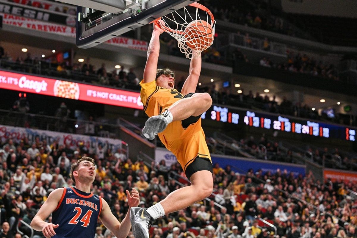 Dec 20, 2025; Iowa City, Iowa, USA; Iowa Hawkeyes guard Isaia Howard (23) completes a slam dunk as Bucknell Bison guard Achile Spadone (24) defends during the first half at Casey’s Center. Mandatory Credit: Jeffrey Becker-Imagn Images
