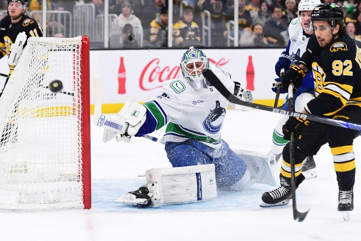 Dec 20, 2025; Boston, Massachusetts, USA; Vancouver Canucks goaltender Kevin Lankinen (32) deflects the puck in the corner past Boston Bruins center Marat Khusnutdinov (92) during the first period at TD Garden. Mandatory Credit: Bob DeChiara-Imagn Images