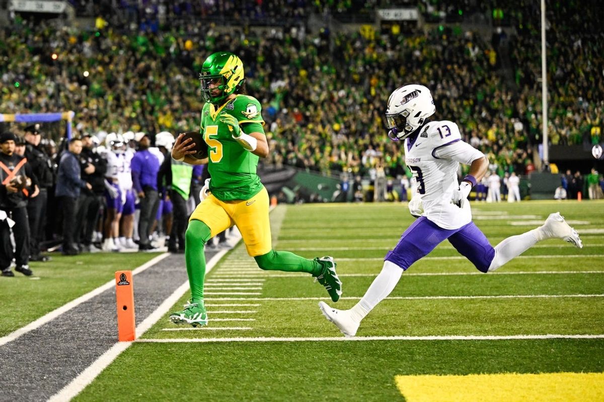 Dec 20, 2025; Eugene, OR, USA; Oregon Ducks quarterback Dante Moore (5) rushes for a touchdown as James Madison Dukes safety Tyler Brown (13) defends during the first quarter at Autzen Stadium. Mandatory Credit: Troy Wayrynen-Imagn Images