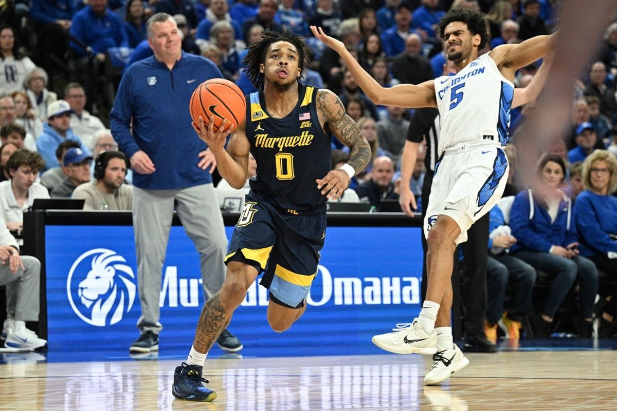 Dec 20, 2025; Omaha, Nebraska, USA;  Marquette Golden Eagles guard Nigel James Jr. (0) drives past Creighton Bluejays guard Nik Graves (5) during the first half at CHI Health Center Omaha. Mandatory Credit: Steven Branscombe-Imagn Images