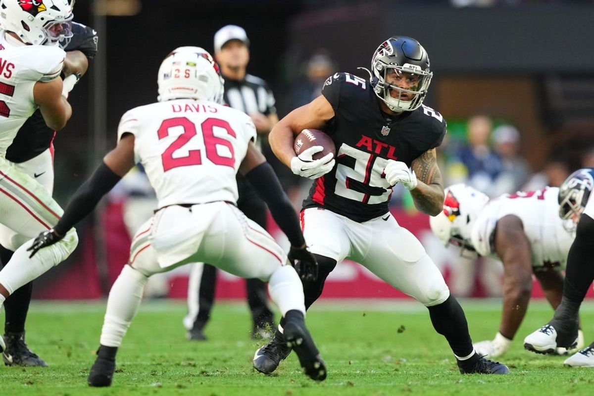 Dec 21, 2025; Glendale, Arizona, USA;  Atlanta Falcons running back Tyler Allgeier (25) carries the ball as Arizona Cardinals cornerback Jaden Davis (26) defends during the first half at State Farm Stadium. Mandatory Credit: Joe Camporeale-Imagn Images