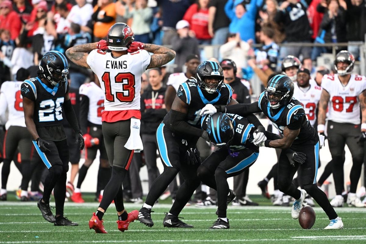 Dec 21, 2025; Charlotte, North Carolina, USA; Carolina Panthers safety Lathan Ransom (22) celebrates with cornerback Chau Smith-Wade (26) and linebacker Nic Scourton (11) and safety Nick Scott (21) after intercepting the ball to seal the victory in the fourth quarter as Tampa Bay Buccaneers wide receiver Mike Evans (13) looks on at Bank of America Stadium. Mandatory Credit: Bob Donnan-Imagn Images