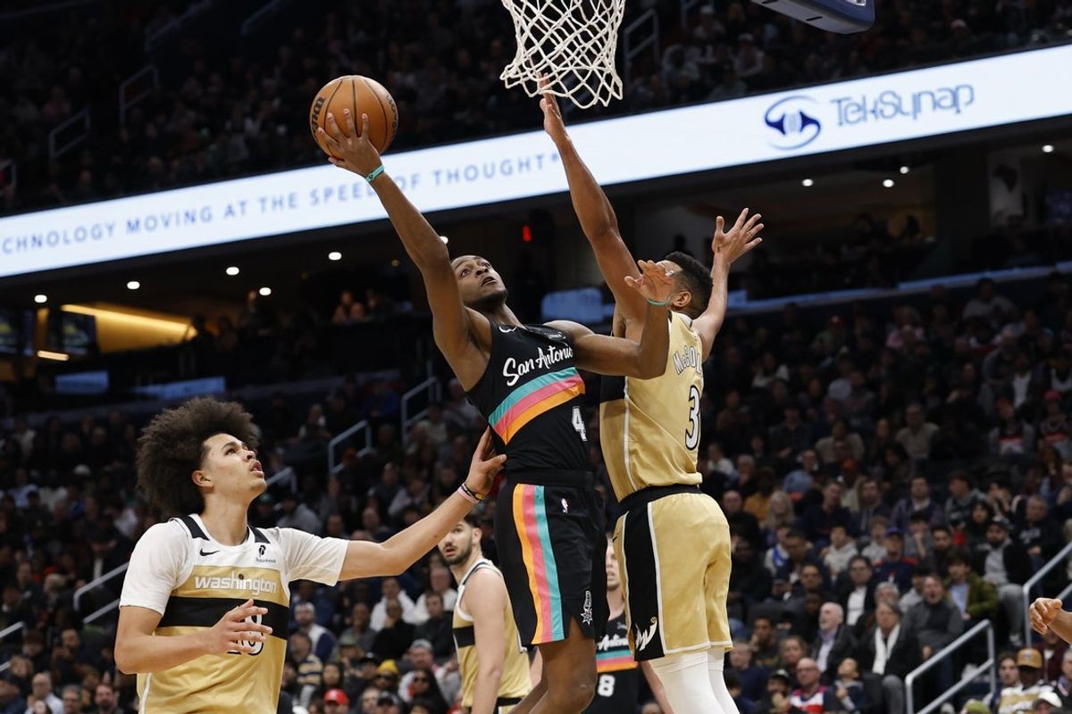 Dec 21, 2025; Washington, District of Columbia, USA; San Antonio Spurs guard De'Aaron Fox (4) shoots the ball as Washington Wizards guard CJ McCollum (3) defends in the second quarter at Capital One Arena. Mandatory Credit: Geoff Burke-Imagn Images