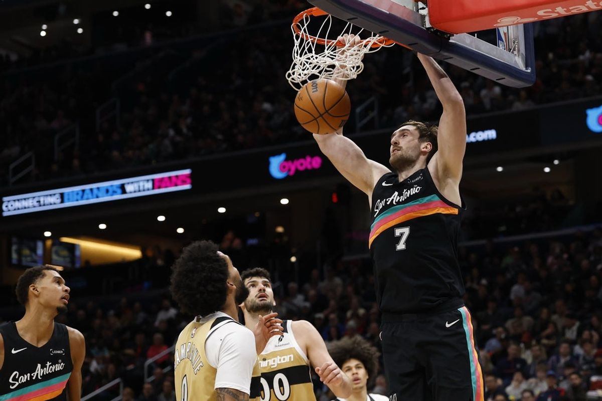 Dec 21, 2025; Washington, District of Columbia, USA; San Antonio Spurs center Luke Kornet (7) dunks the ball as Washington Wizards forward Tristan Vukcevic (00) looks on in the second quarter at Capital One Arena. Mandatory Credit: Geoff Burke-Imagn Images