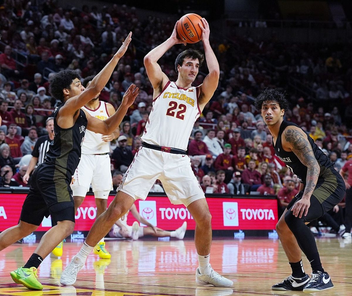 Iowa State Cyclones forward Milan Momcilovic (22) passes the ball between Long Beach State guard Gavin Sykes (11) and guard BeachRob Diaz III (0) during the first half in the NCAA men’s basketball on Dec. 21, 2025, at Hilton Coliseum in Ames, Iowa.