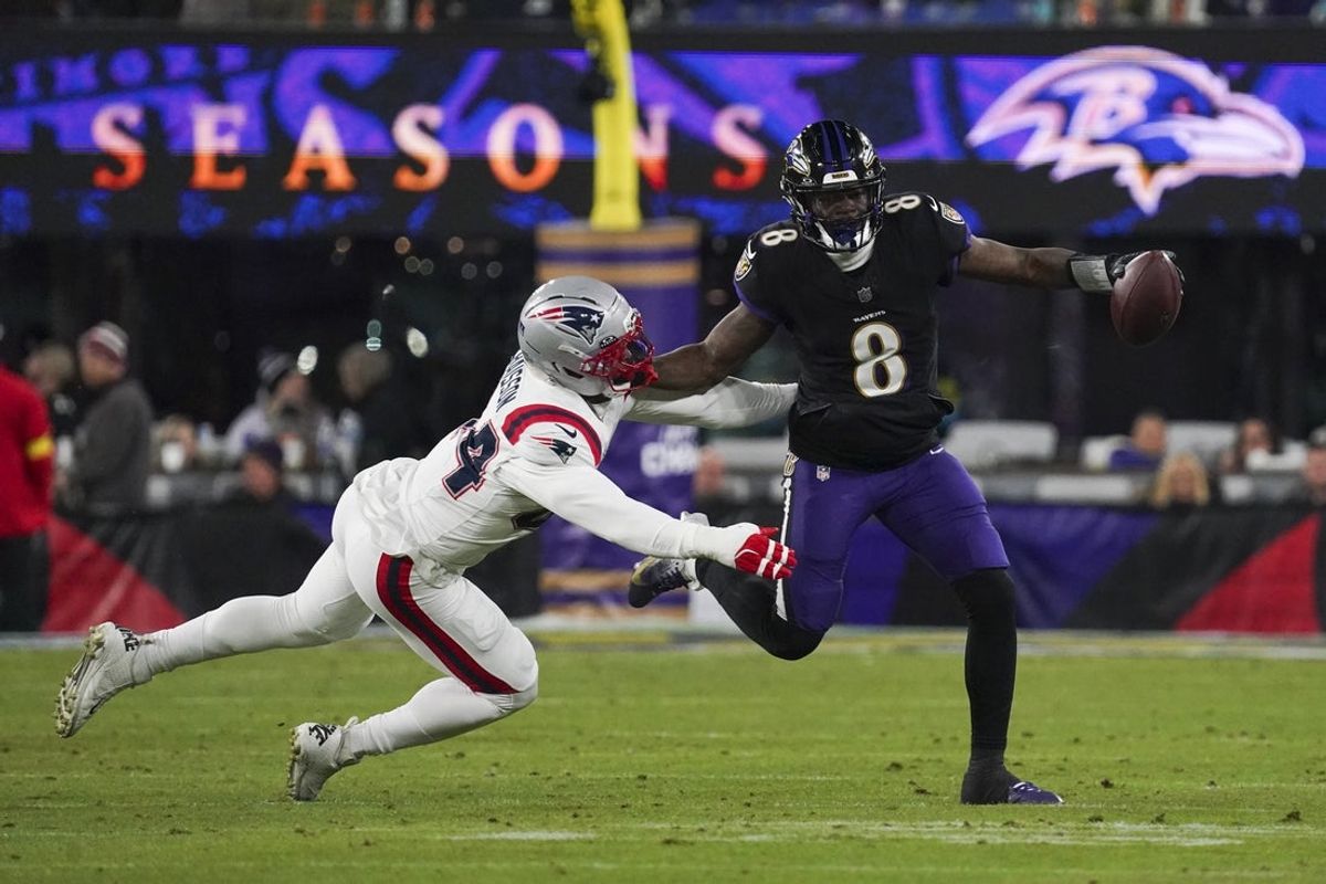Dec 21, 2025; Baltimore, Maryland, USA;  Baltimore Ravens quarterback Lamar Jackson (8) stiff arms New England Patriots linebacker K'Lavon Chaisson (44) during the first half of the game at M&T Bank Stadium. Mandatory Credit: James Lang-Imagn Images