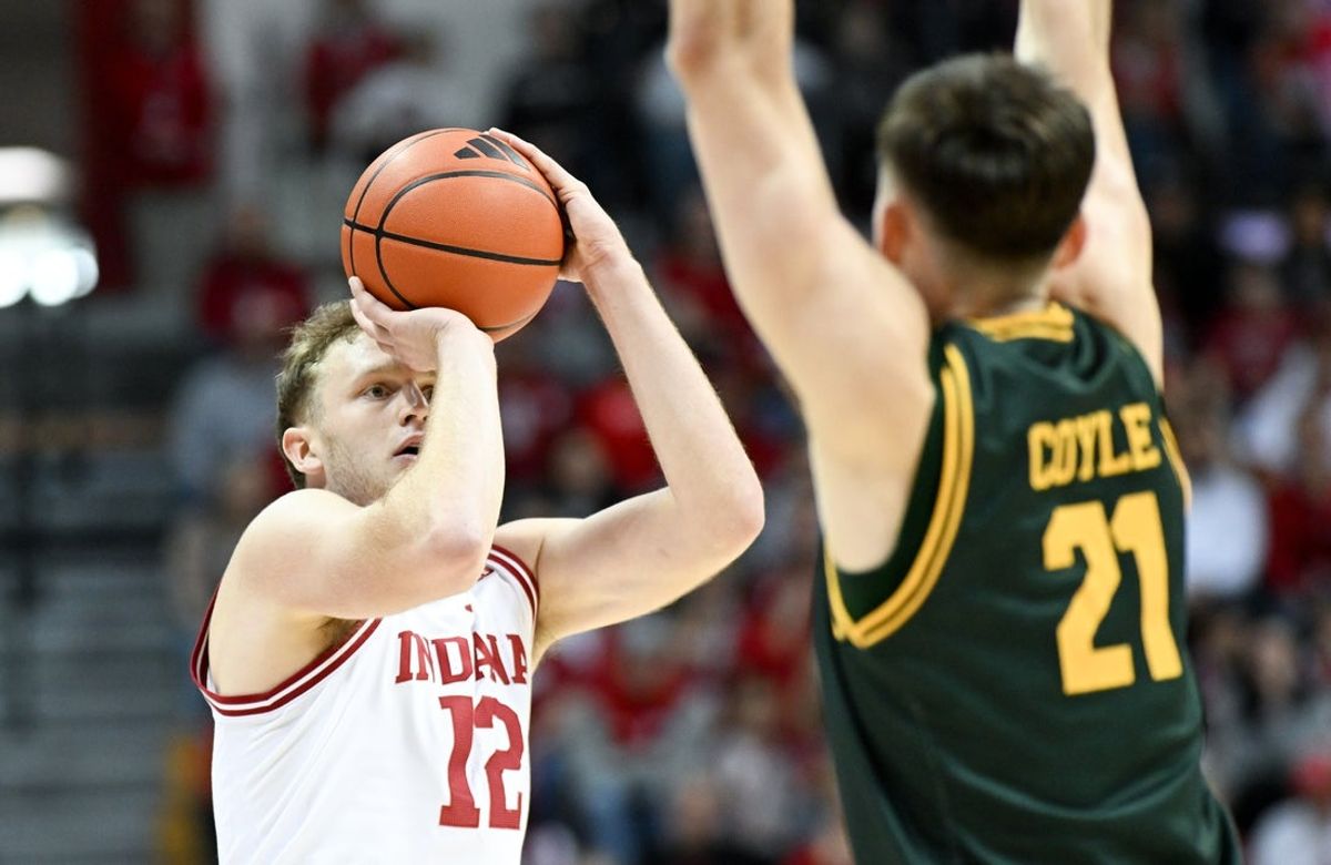 Dec 22, 2025; Bloomington, Indiana, USA; Indiana Hoosiers forward Tucker Devries (12) shoots the ball over Siena Saints forward Brendan Coyle (21) during the first half at Simon Skjodt Assembly Hall. Mandatory Credit: Robert Goddin-Imagn Images