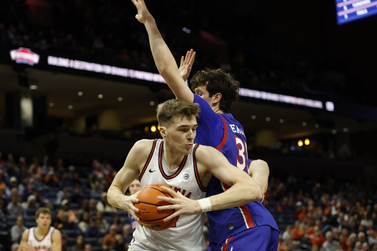 Dec 22, 2025; Charlottesville, Virginia, USA; Virginia Cavaliers center Johann Grunloh (17) drives to the basket around American University Eagles forward Chris Eagan (35) in the second half at John Paul Jones Arena. Mandatory Credit: Geoff Burke-Imagn Images