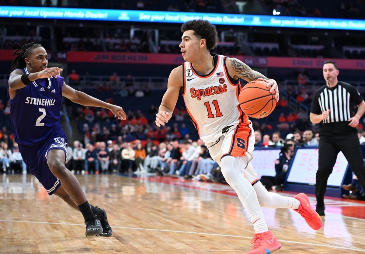 Dec 22, 2025; Syracuse, New York, USA; Syracuse Orange guard Naithan George (11) drives the baseline with Stonehill Skyhawks guard Trenton Ruth (2) defending in the second half at the JMA Wireless Dome. Mandatory Credit: Mark Konezny-Imagn Images