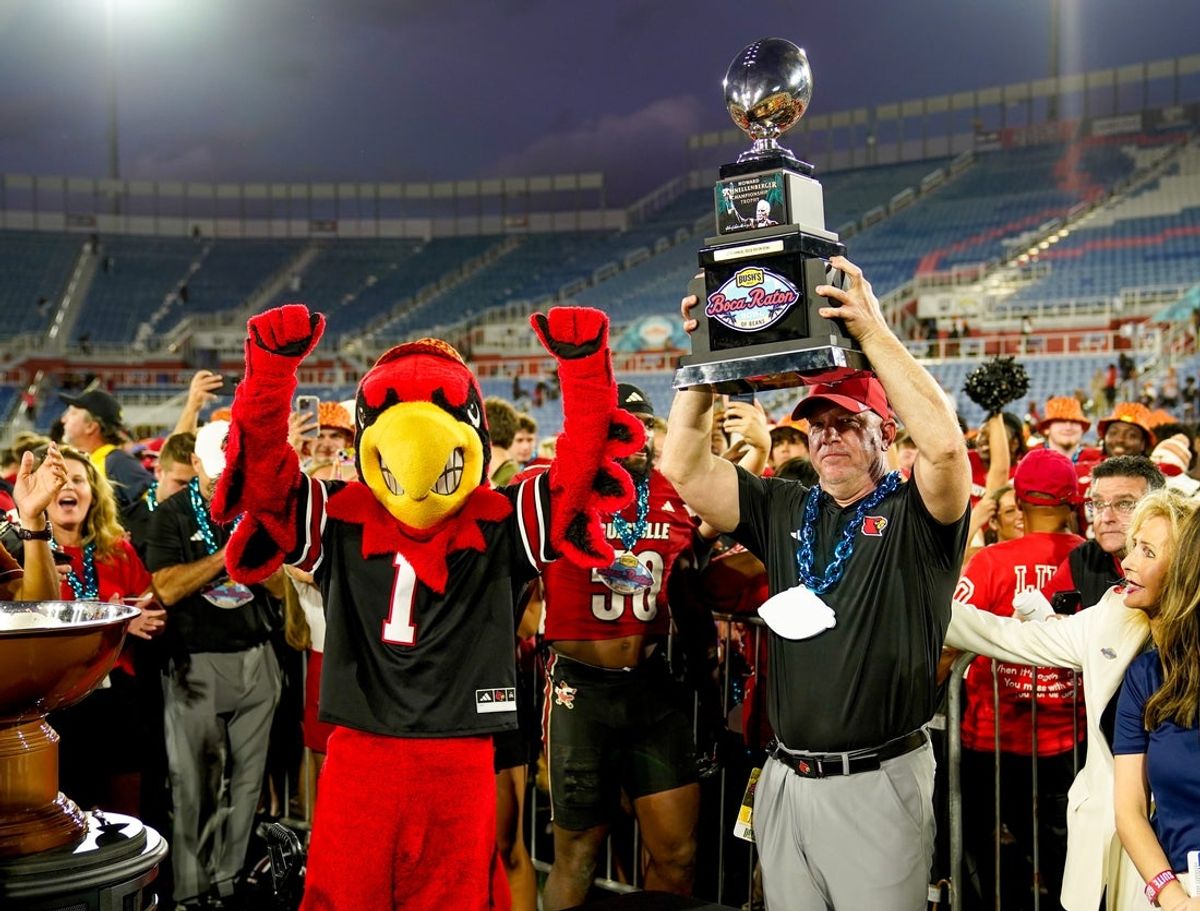Dec 23, 2025; Boca Raton, FL, USA; Louisville Cardinals head coach Jeff Brohm raises the trophy after defeating the Toledo Rockets in the Boca Raton Bowl at Flagler CU Stadium. Mandatory Credit: Jeff Romance-Imagn Images