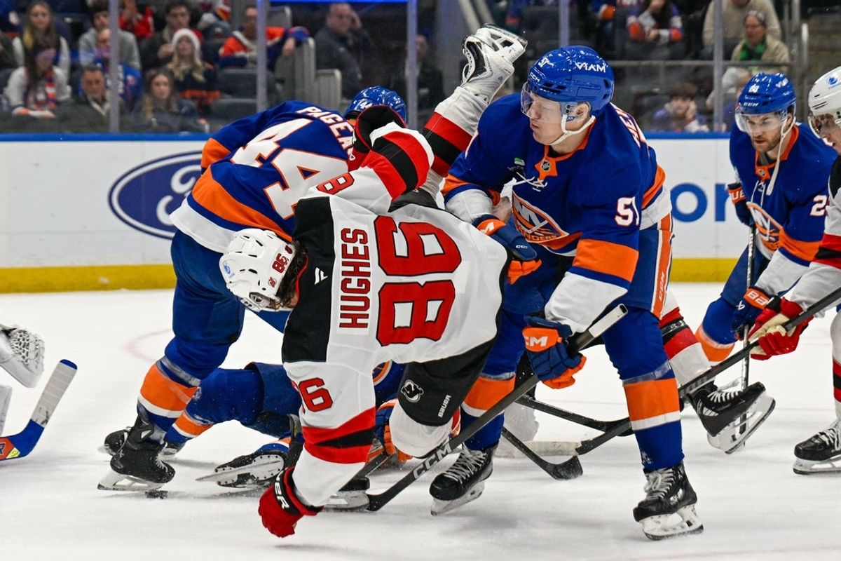 Dec 23, 2025; Elmont, New York, USA;  New York Islanders left wing Emil Heineman (51) checks New Jersey Devils center Jack Hughes (86) battling for a loose puck during the first period at UBS Arena. Mandatory Credit: Dennis Schneidler-Imagn Images