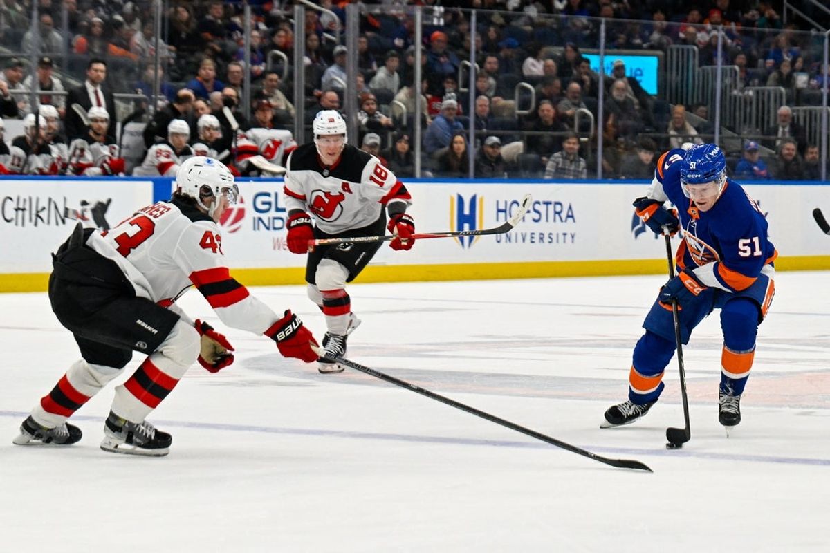 Dec 23, 2025; Elmont, New York, USA;  New Jersey Devils defenseman Luke Hughes (43) defends against New York Islanders left wing Emil Heineman (51) during the second period at UBS Arena. Mandatory Credit: Dennis Schneidler-Imagn Images