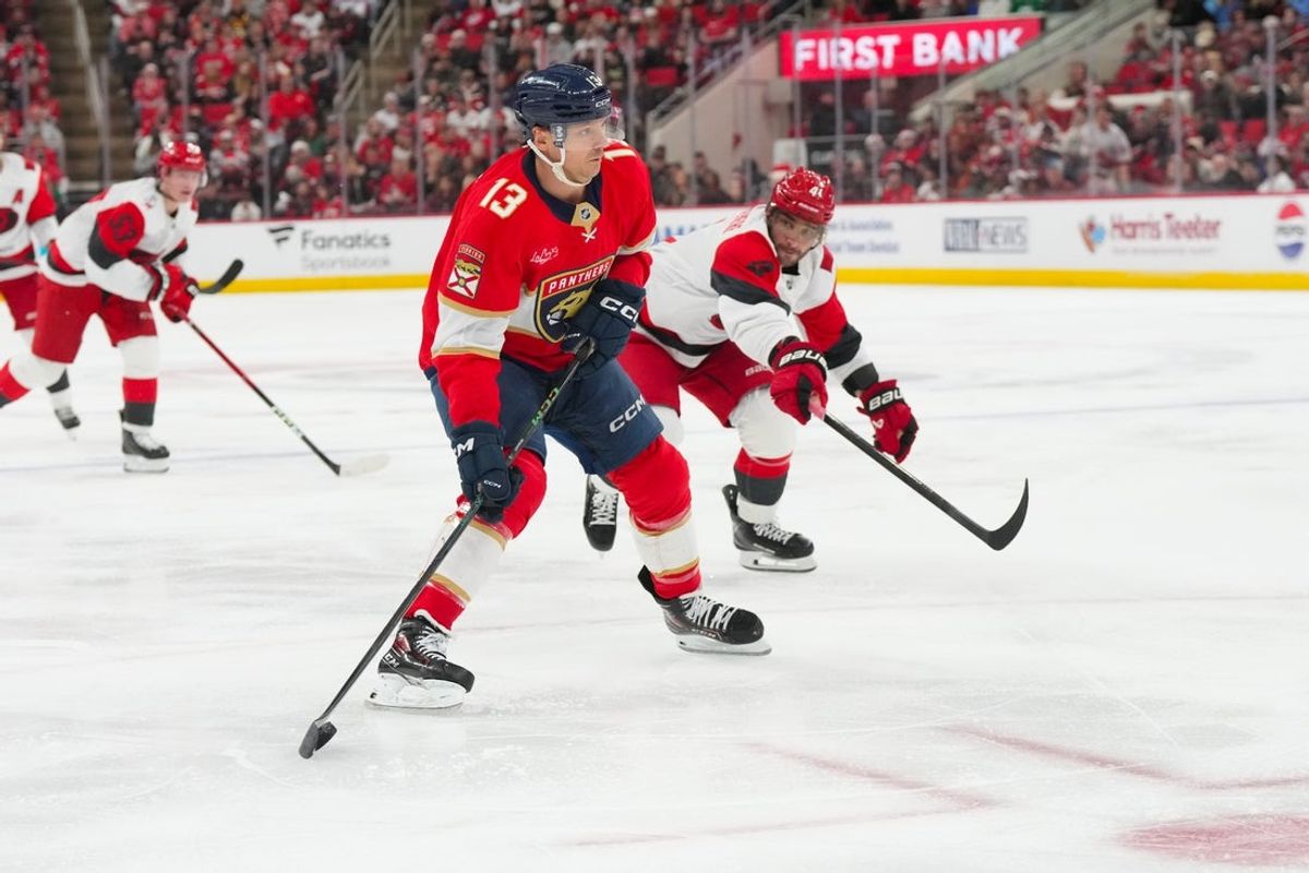 Dec 23, 2025; Raleigh, North Carolina, USA;  Florida Panthers center Sam Reinhart (13) skates with the puck past Carolina Hurricanes defenseman Shayne Gostisbehere (4) during the second period at Lenovo Center. Mandatory Credit: James Guillory-Imagn Images
