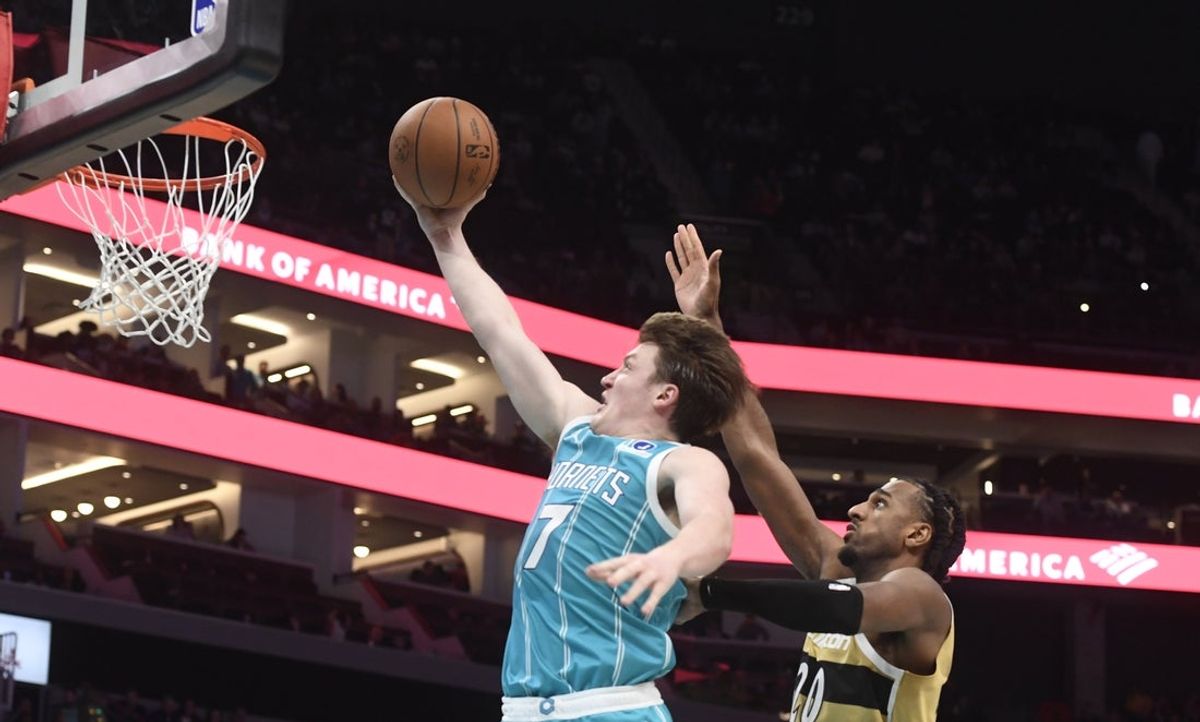 Dec 23, 2025; Charlotte, North Carolina, USA;  Charlotte Hornets forward Kon Knueppel (7) drives in past Washington Wizards center Alex Sarr (20) during the second half at the Spectrum Center. Mandatory Credit: Sam Sharpe-Imagn Images