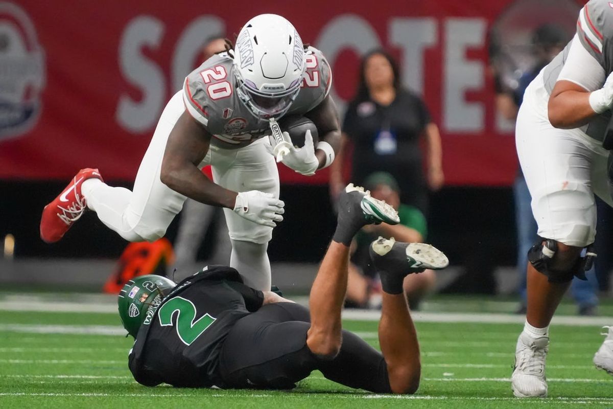 Dec 23, 2025; Frisco, TX, USA;  UNLV Rebels running back Jaylon Glover (20) is tipped up by. Ohio Bobcats safety DJ Walker (2) during the first half at the Ford Center at The Star. Mandatory Credit: Raymond Carlin III-Imagn Images