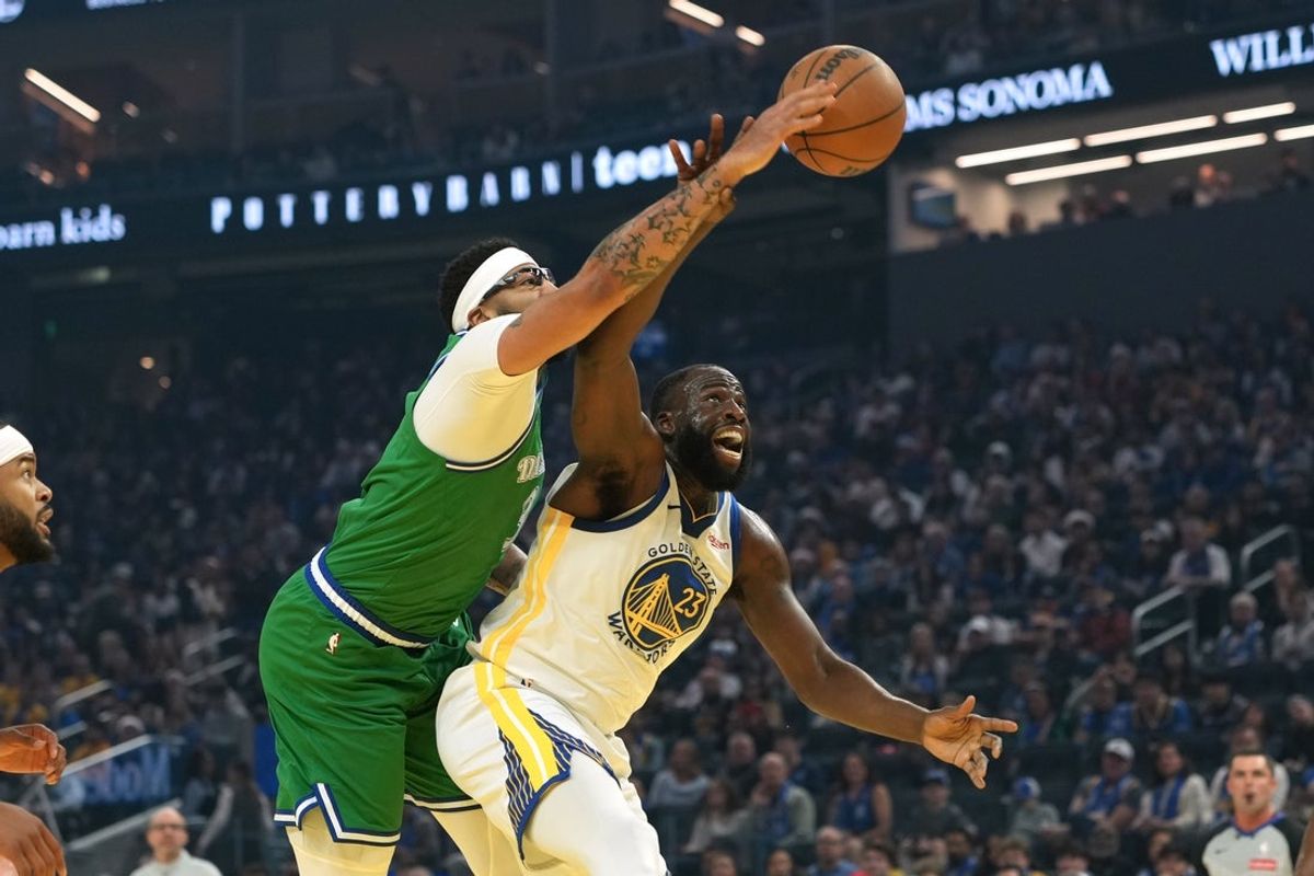 Dec 25, 2025; San Francisco, California, USA; Golden State Warriors forward Draymond Green (23) rebounds against Dallas Mavericks forward Anthony Davis (center left) during the first quarter at Chase Center. Mandatory Credit: Darren Yamashita-Imagn Images