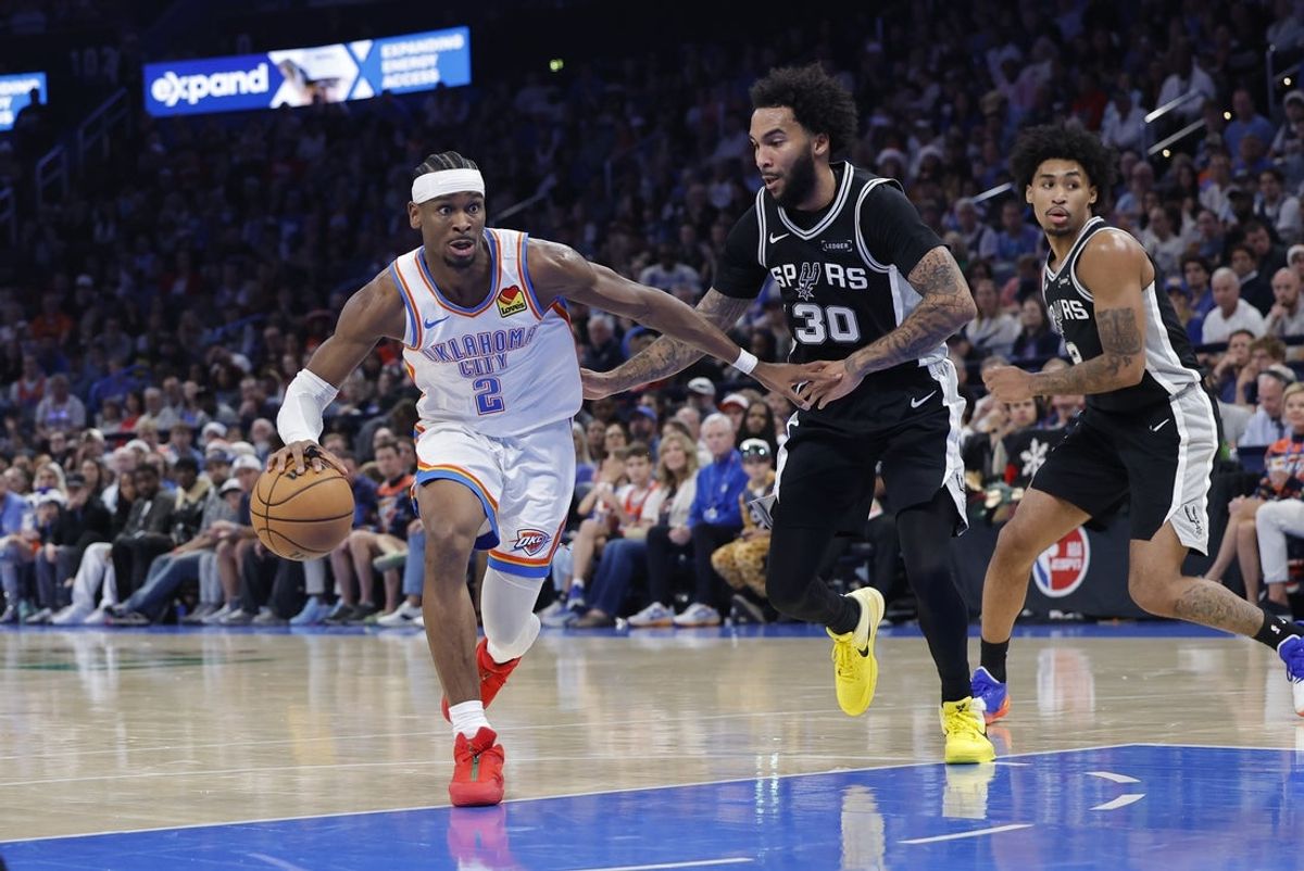 Dec 25, 2025; Oklahoma City, Oklahoma, USA; Oklahoma City Thunder guard Shai Gilgeous-Alexander (2) drives around San Antonio Spurs forward Julian Champagnie (30) during the second half at Paycom Center. Mandatory Credit: Alonzo Adams-Imagn Images