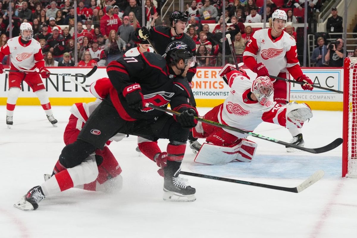 Dec 27, 2025; Raleigh, North Carolina, USA;  Detroit Red Wings center Emmitt Finnie (58) blocks the shot attempt by Carolina Hurricanes left wing Mark Jankowski (77) during the first period at Lenovo Center. Mandatory Credit: James Guillory-Imagn Images