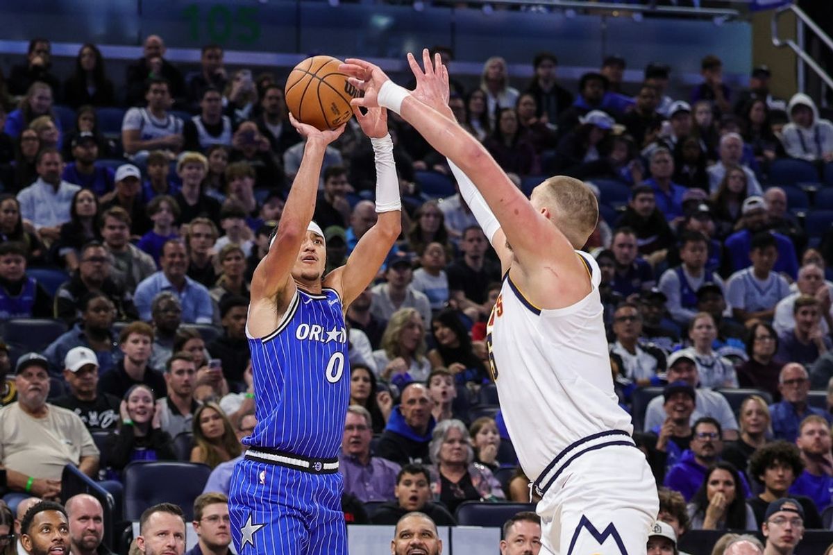 Dec 27, 2025; Orlando, Florida, USA; Orlando Magic guard Anthony Black (0) shoots a three point basket against Denver Nuggets center Nikola Jokic (15) during the first quarter at Kia Center. Mandatory Credit: Mike Watters-Imagn Images