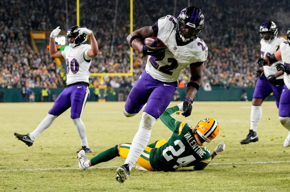 Dec 27, 2025; Green Bay, Wisconsin, USA; Baltimore Ravens running back Derrick Henry (22) runs for a touchdown past Green Bay Packers cornerback Carrington Valentine (24) during the second quarter at Lambeau Field. Mandatory Credit: Jeff Hanisch-Imagn Images