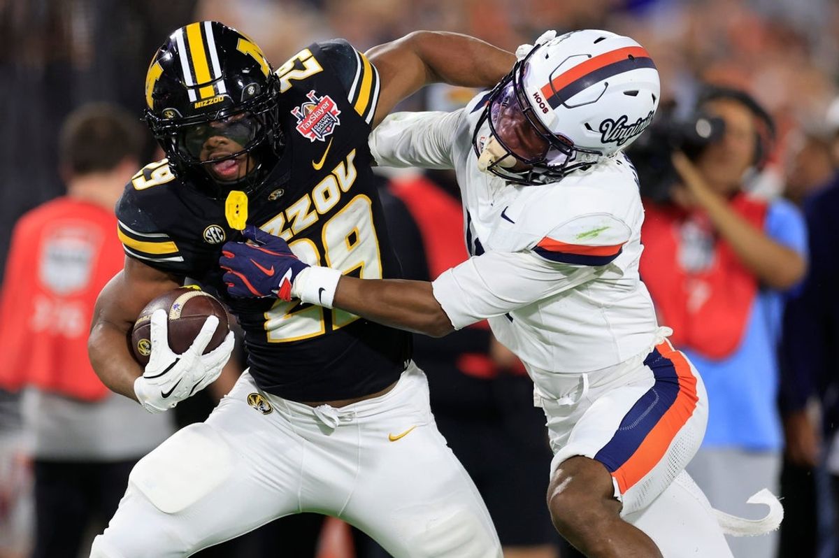 Missouri Tigers running back Ahmad Hardy (29) fends off Virginia Cavaliers cornerback Emmanuel Karnley (19) during the first quarter of the TaxSlayer Gator Bowl at EverBank Stadium, Saturday, Dec. 27, 2025, in Jacksonville. Fla.