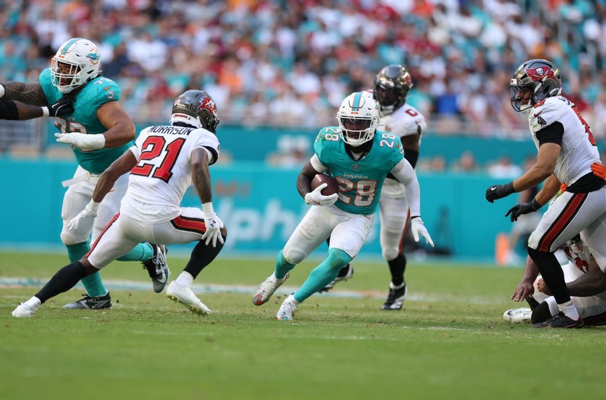 Dec 28, 2025; Miami Gardens, Florida, USA; Miami Dolphins running back De'Von Achane (28) runs for a gain past Tampa Bay Buccaneers cornerback Benjamin Morrison (21) during the third quarter at Hard Rock Stadium. Mandatory Credit: Nathan Ray Seebeck-Imagn Images