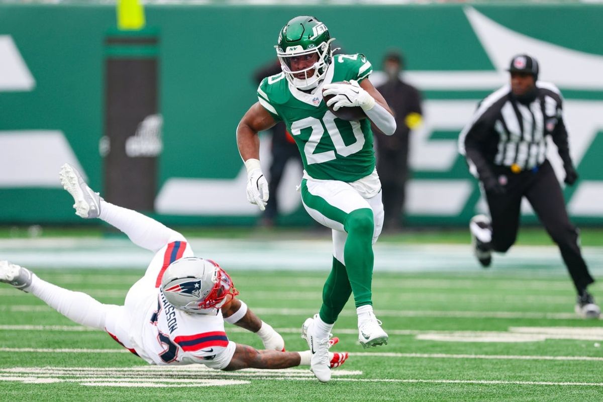 Dec 28, 2025; East Rutherford, New Jersey, USA; New York Jets running back Breece Hall (20) carries the ball asNew England Patriots linebacker K'Lavon Chaisson (44) pursues during the first half at MetLife Stadium. Mandatory Credit: Vincent Carchietta-Imagn Images