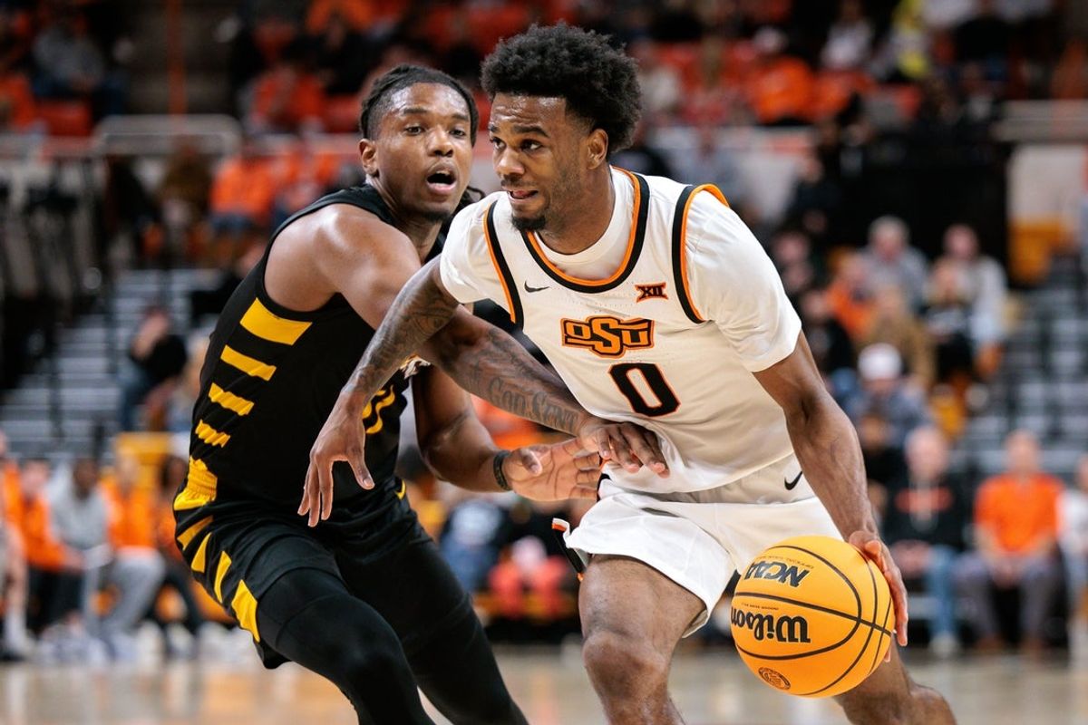 Dec 29, 2025; Stillwater, Oklahoma, USA; Oklahoma State Cowboys player Jaylen Curry drives to the basket around Bethune-Cookman Wildcats player Jordan Johnson during the first half at Gallagher-Iba Arena. Mandatory Credit: William Purnell-Imagn Images