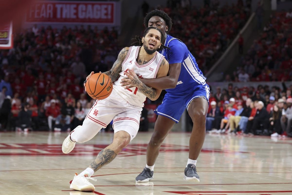 Dec 29, 2025; Houston, Texas, USA; Houston Cougars guard Emanuel Sharp (21) drives with the ball as Middle Tennessee Blue Raiders guard Kamari Lands (22) defends during the second half at Fertitta Center. Mandatory Credit: Troy Taormina-Imagn Images
