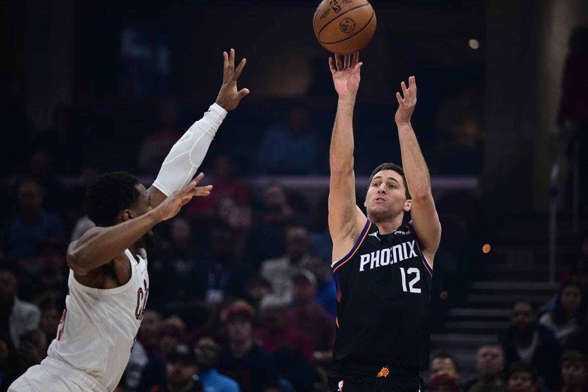 Dec 31, 2025; Cleveland, Ohio, USA; Phoenix Suns guard Collin Gillespie (12) shoots a three point shot over rCleveland Cavaliers guard Donovan Mitchell (45) during the first half  at Rocket Arena. Mandatory Credit: David Dermer-Imagn Images