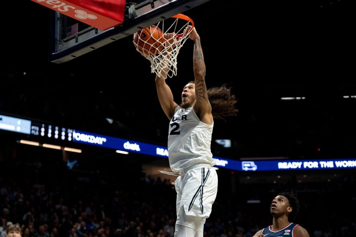 Xavier Musketeers forward Tre Carroll (12) dunks as UConn Huskies center Tarris Reed Jr. (5) looks on in the first half of the NCAA basketball game at the Cintas Center in Cincinnati on Dec. 31, 2025.