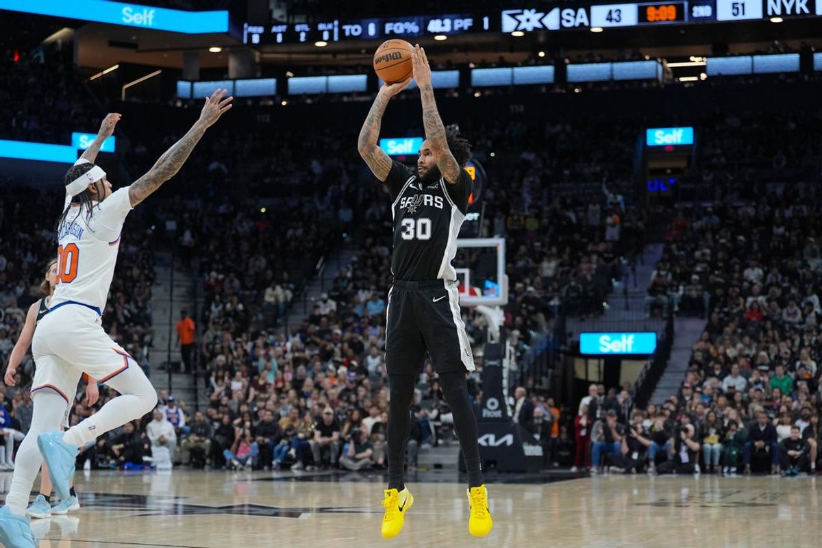 Dec 31, 2025; San Antonio, Texas, USA;  San Antonio Spurs forward Julian Champagnie (30) shoots in front of New York Knicks guard Jordan Clarkson (00) in the first half at Frost Bank Center. Mandatory Credit: Daniel Dunn-Imagn Images