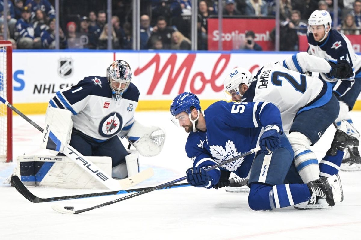 Jan 1, 2026; Toronto, Ontario, CAN;   Toronto Maple Leafs forward Nicolas Roy (55) tries to get off a shot after being knocked down by Winnipeg Jets defenseman Dylan DeMelo (2) in front of goalie Eric Comrie (1) in the first period at Scotiabank Arena. Mandatory Credit: Dan Hamilton-Imagn Images