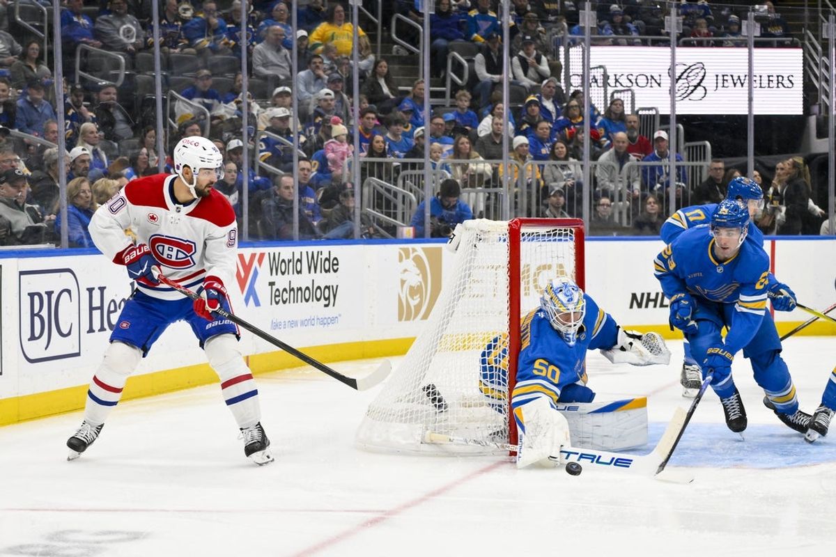 Jan 3, 2026; St. Louis, Missouri, USA; St. Louis Blues goaltender Jordan Binnington (50) and defenseman Logan Mailloux (23) defend the net against Montreal Canadiens center Joe Veleno (90) during the first period at Enterprise Center. Mandatory Credit: Jeff Curry-Imagn Images