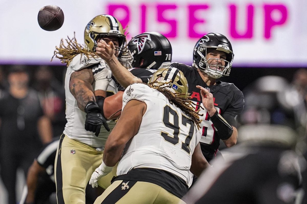 Jan 4, 2026; Atlanta, Georgia, USA; Atlanta Falcons quarterback Kirk Cousins (18) throws an incomplete pass as he is hit by New Orleans Saints defensive end Chase Young (99) and defensive tackle Khristian Boyd (97) during the first half at Mercedes-Benz Stadium. Mandatory Credit: Dale Zanine-Imagn Images