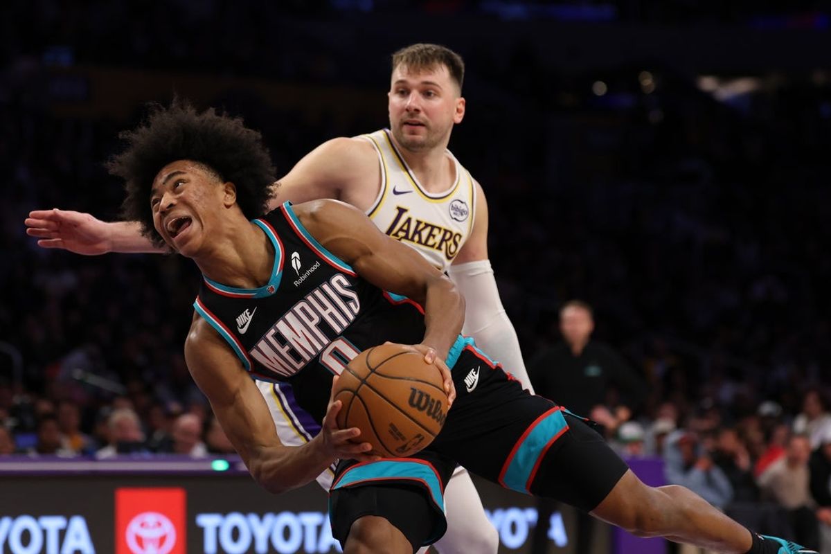 Jan 4, 2026; Los Angeles, California, USA;  Memphis Grizzlies forward Jaylen Wells (0) attempts to shoot the ball against Los Angeles Lakers guard Luka Doncic (77) during the fourth quarter at Crypto.com Arena. Mandatory Credit: Kiyoshi Mio-Imagn Images