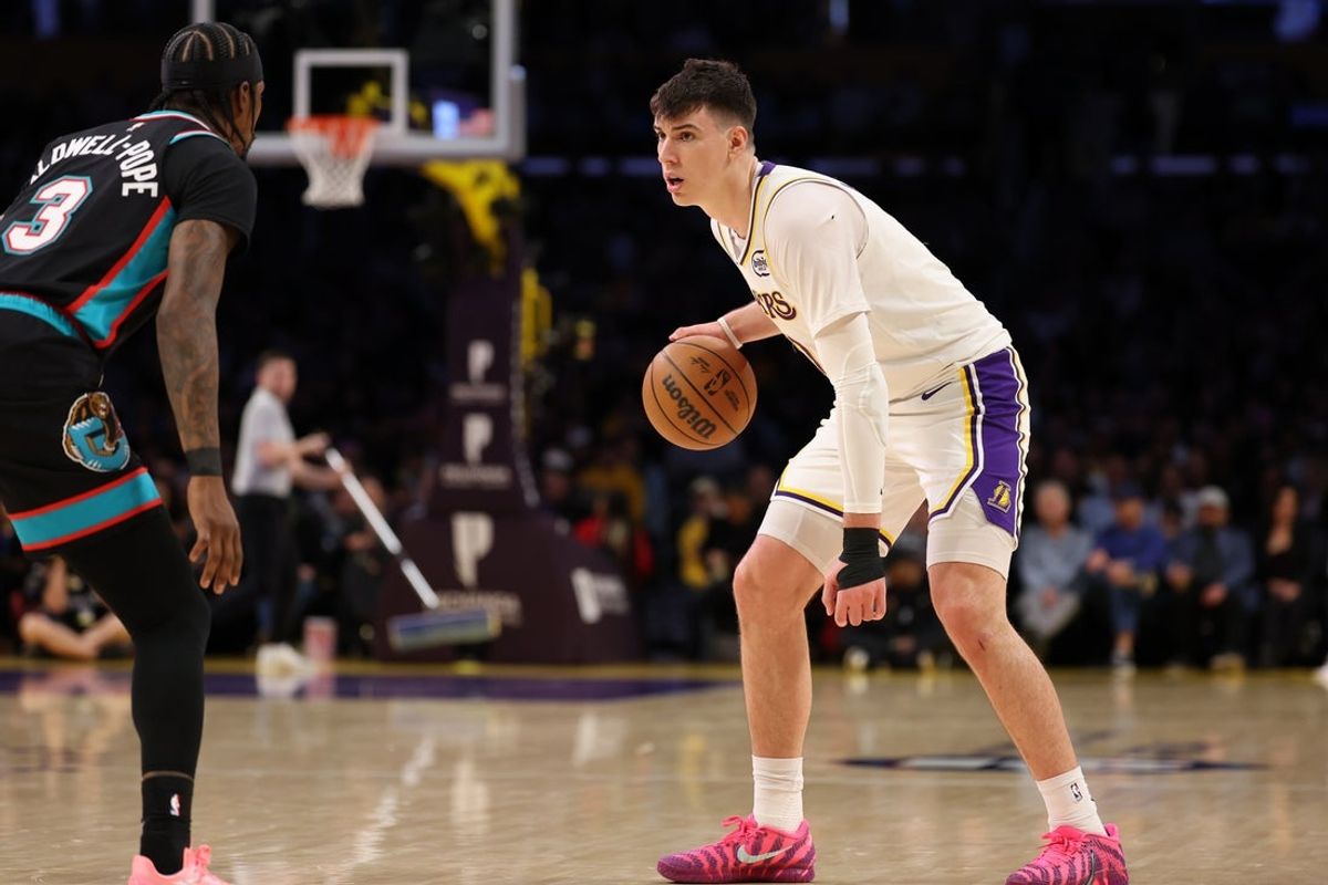 Jan 4, 2026; Los Angeles, California, USA;  Los Angeles Lakers forward Jake LaRavia (12) dribbles the ball against Memphis Grizzlies guard Kentavious Caldwell-Pope (3) during the first half at Crypto.com Arena. Mandatory Credit: Kiyoshi Mio-Imagn Images