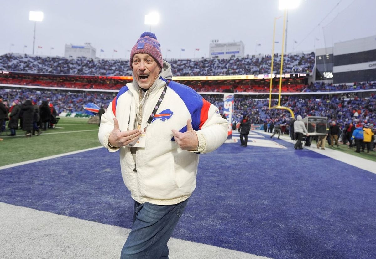 Jim Kelly, ex-quarterback do Bills, aponta para sua jaqueta ao entrar em campo antes das apresentações do time. Este foi o último jogo em casa do Bills no Highmark Stadium, em Orchard Park, em 4 de janeiro de 2026. O time jogará no próximo ano no estádio do outro lado da rua.