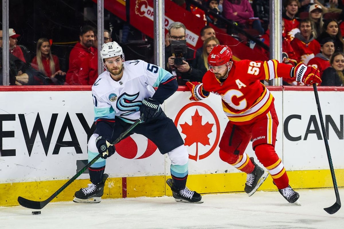 Jan 5, 2026; Calgary, Alberta, CAN; Seattle Kraken center Shane Wright (51) controls the puck against Calgary Flames defenseman MacKenzie Weegar (52) during the first period at Scotiabank Saddledome. Mandatory Credit: Sergei Belski-Imagn Images
