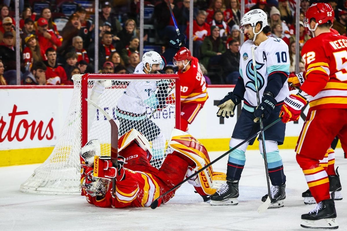 Jan 5, 2026; Calgary, Alberta, CAN; Calgary Flames goaltender Dustin Wolf (32) and Seattle Kraken center Matty Beniers (10) collide during the third period at Scotiabank Saddledome. Mandatory Credit: Sergei Belski-Imagn Images